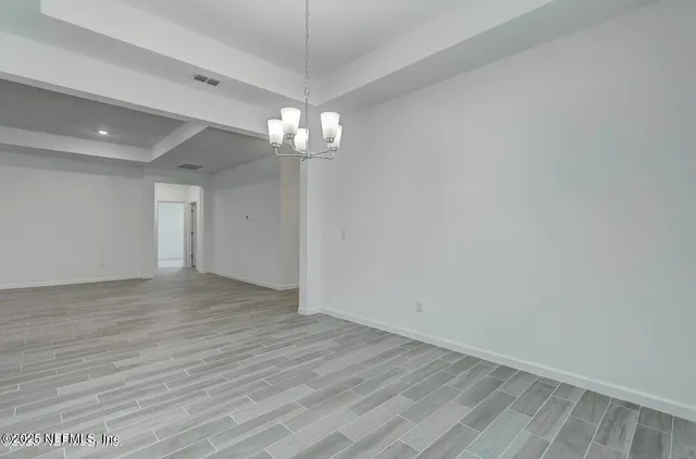a view of empty room with wooden floor and chandelier