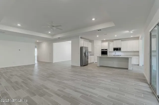 a view of kitchen with kitchen island a sink wooden floor and a refrigerator