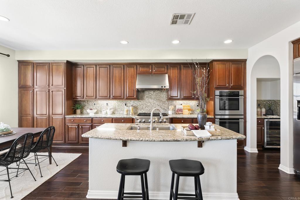 1407 Eclipse Drive San Marcos, CA 92078 - Photo 9 of 32 a kitchen with stainless steel appliances granite countertop a kitchen island hardwood floor sink and stove