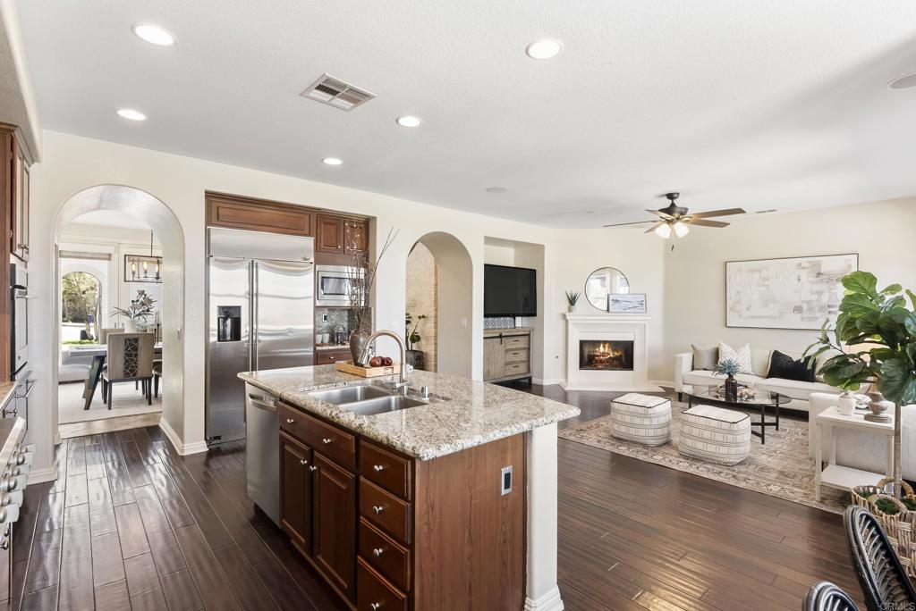 1407 Eclipse Drive San Marcos, CA 92078 - Photo 10 of 32 a large kitchen with stainless steel appliances kitchen island granite countertop a large island a stove a sink dishwasher and white cabinets with wooden floor