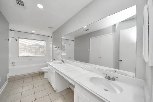 a spacious bathroom with a double vanity sink mirror and bathtub