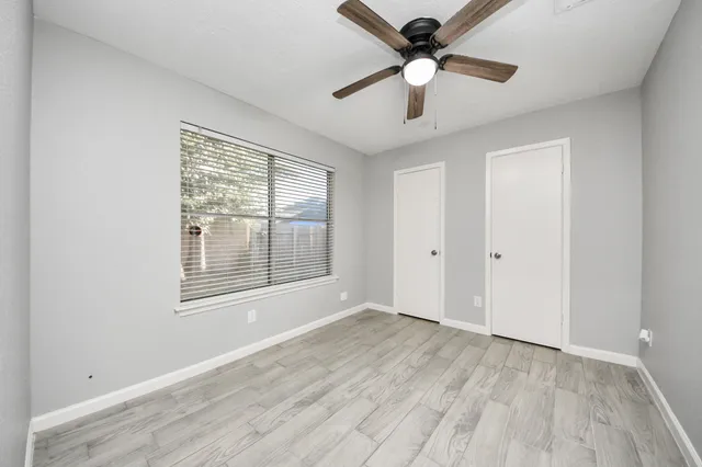 a view of an empty room with a window and a ceiling fan