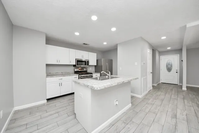 a kitchen with stainless steel appliances kitchen island granite countertop a stove a sink and a refrigerator