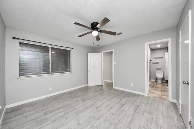 a view of empty room with wooden floor and ceiling fan