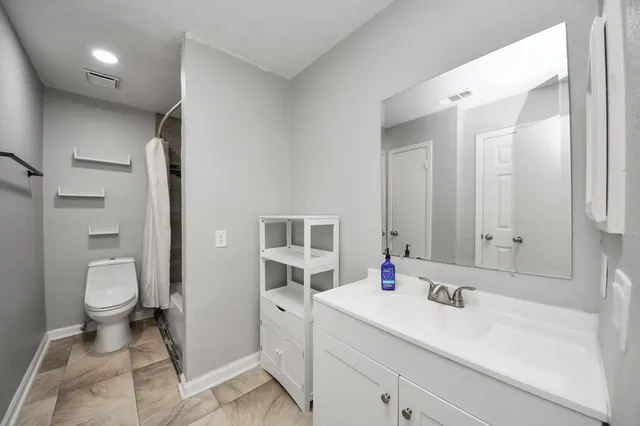 a bathroom with a sink toilet vanity and shower