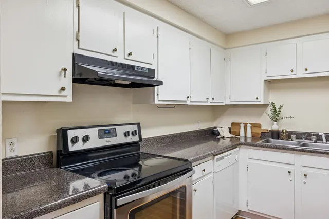 a kitchen with granite countertop a stove and white cabinets
