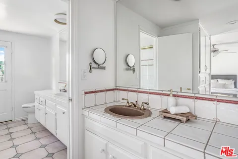a bathroom with a granite countertop sink a toilet a mirror and shower