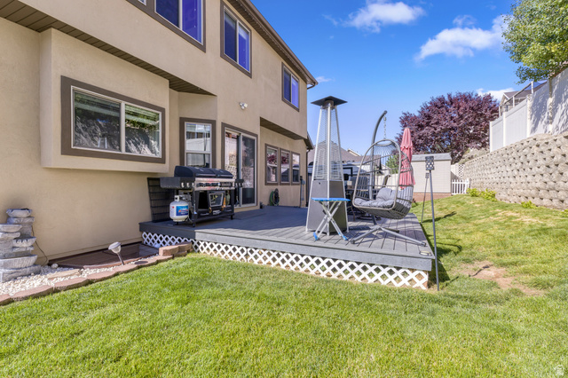 2005 Redtail Way Layton, UT 84040 - Photo 35 of 37 Rear exterior featuring a composite deck with white lattice skirting, direct access via sliding glass doors, a manicured lawn, and a retaining wall