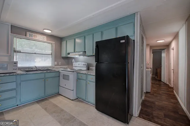 a kitchen with granite countertop a refrigerator and a sink