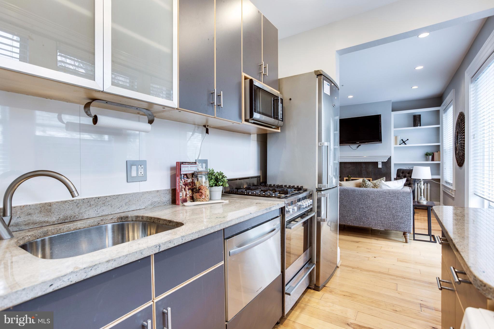 1523 Park Road Northwest, Unit 202 Washington, DC 20010 - Photo 6 of 13 a kitchen with stainless steel appliances granite countertop a stove a sink and a microwave