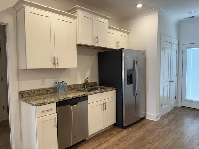a kitchen with stainless steel appliances granite countertop a refrigerator sink and white cabinets
