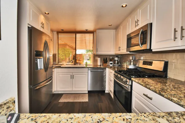 a kitchen with stainless steel appliances granite countertop a stove a sink and a refrigerator