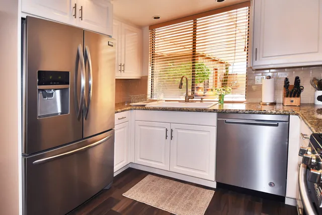 a kitchen with granite countertop stainless steel appliances a refrigerator sink and cabinets
