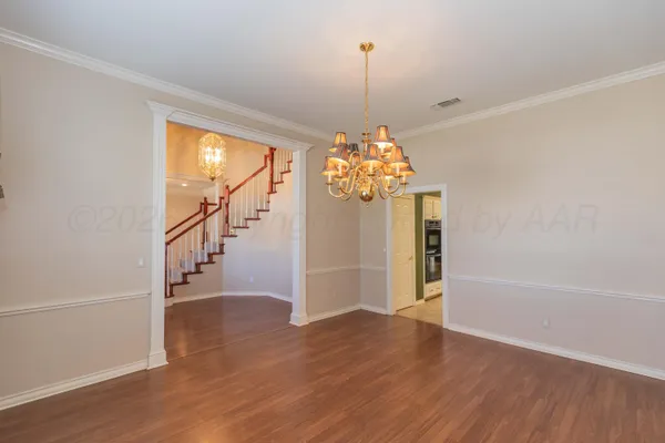 an empty room with a chandelier fan and windows