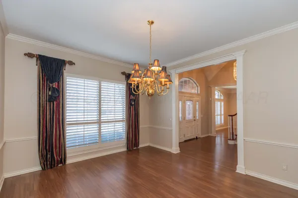 a view of a room with wooden floor chandeliers and kitchen view
