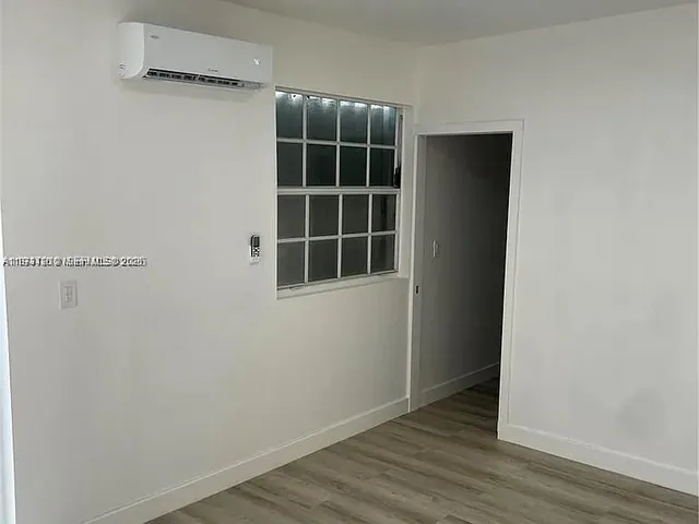 a view of empty room with wooden floor and window