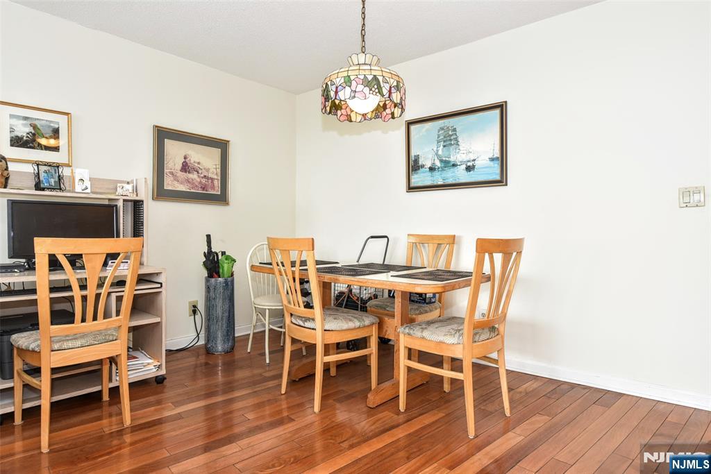 555 North, Unit 8N Fort Lee, NJ 07024 - Photo 11 of 19 a dining room with furniture wooden floor a rug and a chandelier