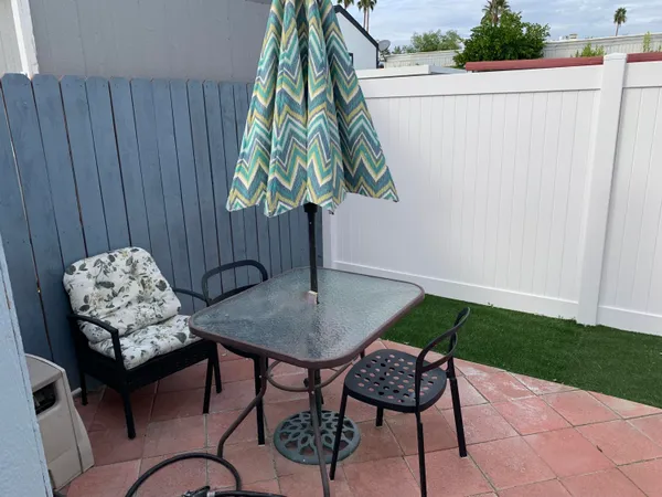 a view of a backyard with chairs and iron fence