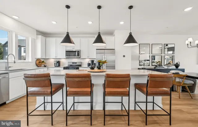 a kitchen with stainless steel appliances kitchen island granite countertop a stove top oven a sink a dining table and chairs with wooden floor