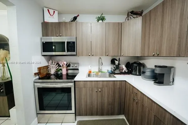 a kitchen with stainless steel appliances a white refrigerator a sink and a stove with wooden floor