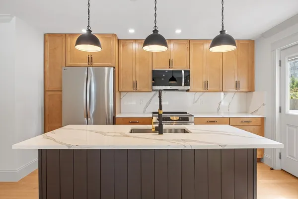 a kitchen with stainless steel appliances a table a sink a refrigerator and wooden floor