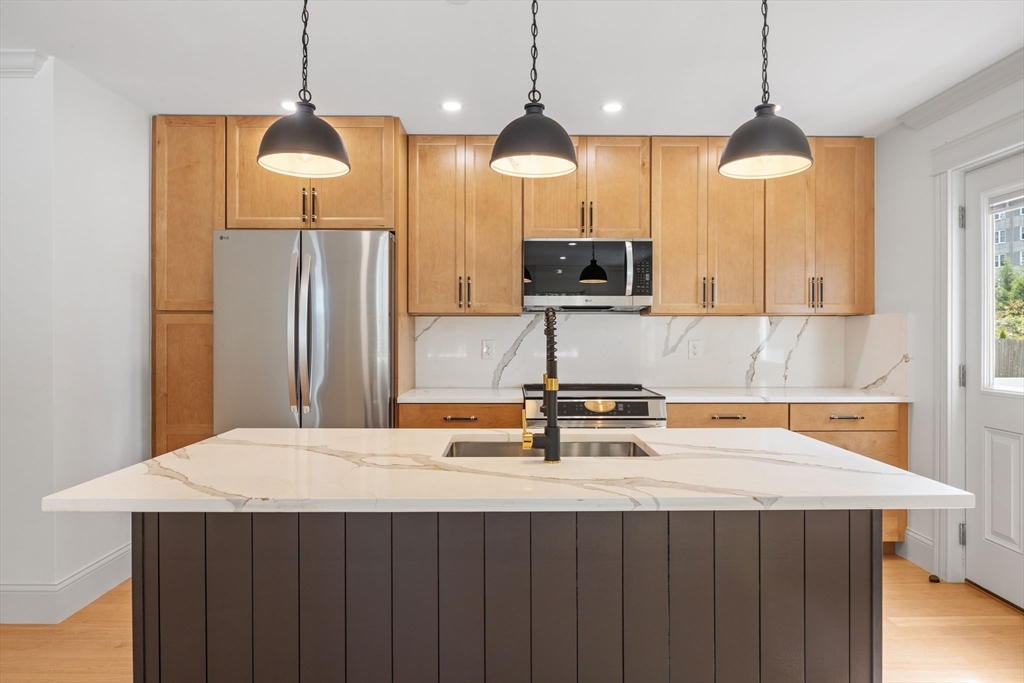9 Swan Street, Unit 3 Beverly, MA 01915 - Photo 4 of 36 a kitchen with stainless steel appliances a table a sink a refrigerator and wooden floor