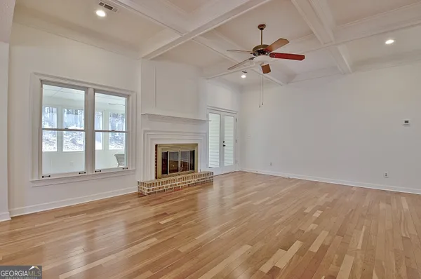 a view of an empty room with wooden floor fireplace and a window