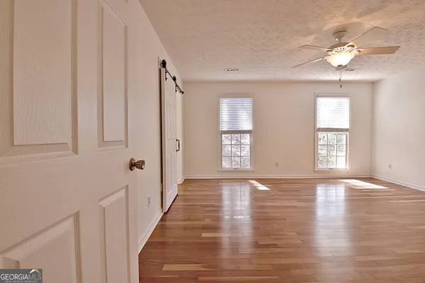 a view of an empty room with wooden floor and window