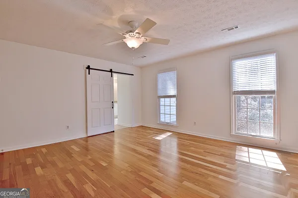 a view of an empty room with a window and wooden floor