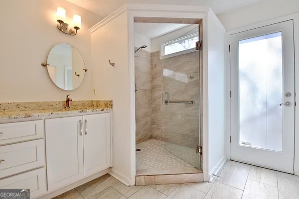 a bathroom with a granite countertop sink a mirror and shower