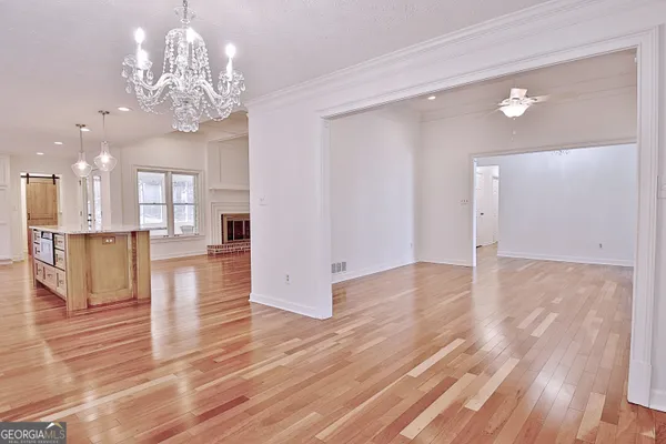 a view of a hallway with wooden floor and chandelier