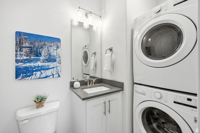 3355 Santa Fe Road Park City, UT 84098 - Photo 11 of 45 Powder room featuring a stacked washer and dryer, a vanity with a dark countertop and undermount sink, and a wall-mounted light fixture