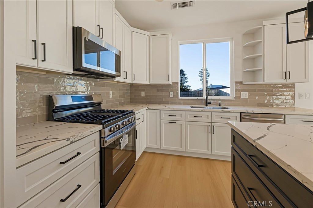 5369 Pentz Road Paradise, CA 95969 - Photo 20 of 42 a kitchen with stainless steel appliances granite countertop white cabinets sink and stove top oven