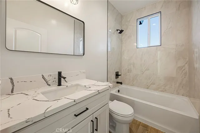 a bathroom with a granite countertop toilet sink and mirror