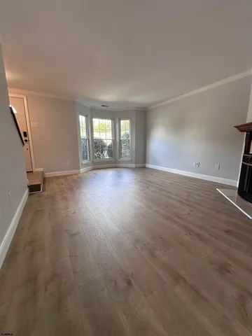 a view of an empty room with window and wooden floor