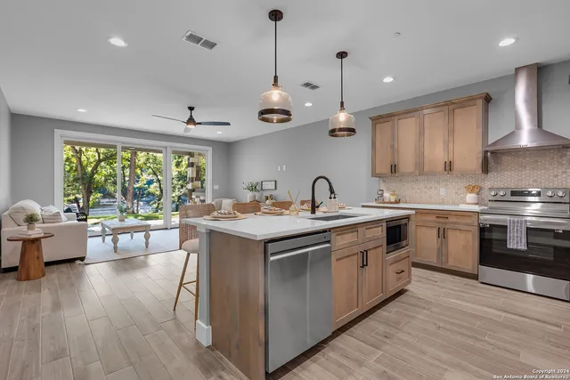 a kitchen with a stove a sink a kitchen island with wooden floor and cabinets