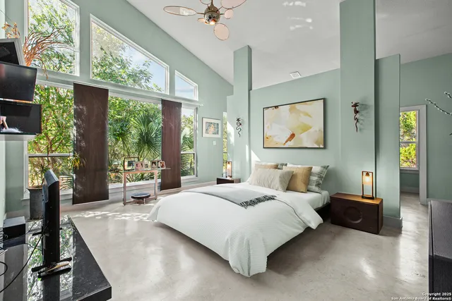 a bedroom with a bed large window and painting on the wall