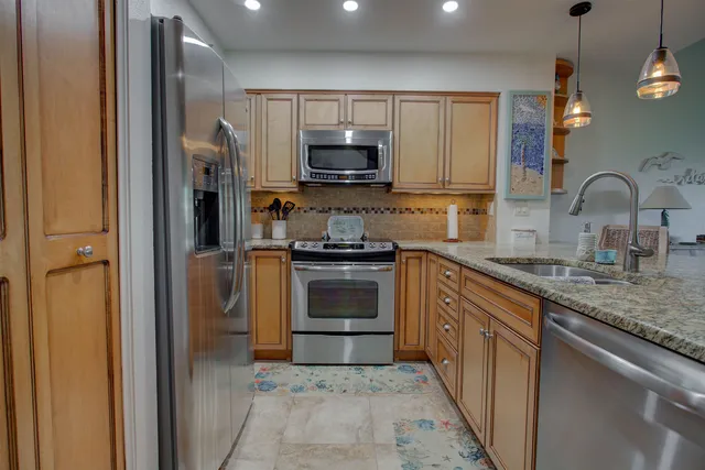a kitchen with stainless steel appliances granite countertop a stove a sink and a refrigerator