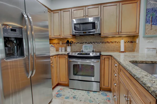 a kitchen with granite countertop a sink stove and refrigerator