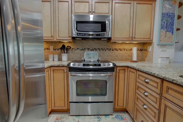 a kitchen with granite countertop a stove top oven microwave and cabinets