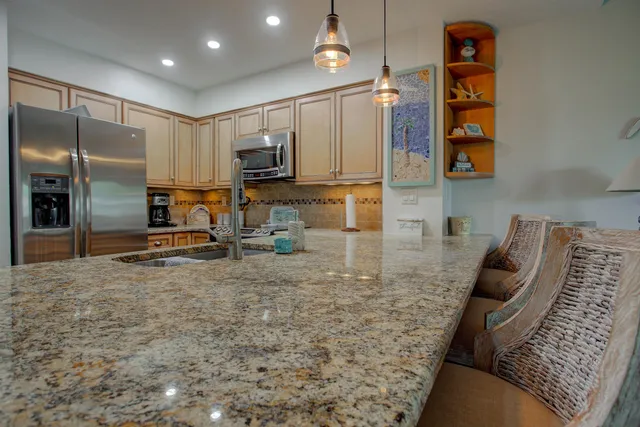 a kitchen with stainless steel appliances kitchen island granite countertop a refrigerator a stove and a sink with wooden floor