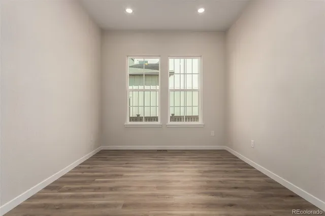 an empty room with wooden floor and windows