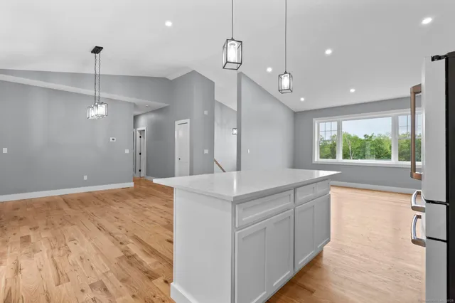 a kitchen with kitchen island a counter top space appliances and a living room view