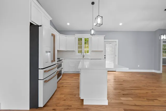 a kitchen with granite countertop a refrigerator and a stove top oven