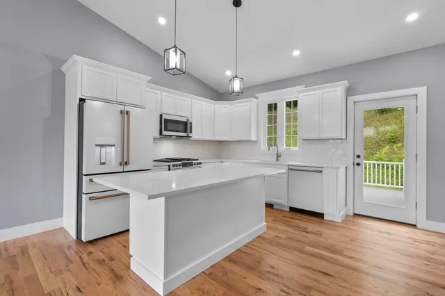 a kitchen with stainless steel appliances granite countertop a sink a stove and refrigerator