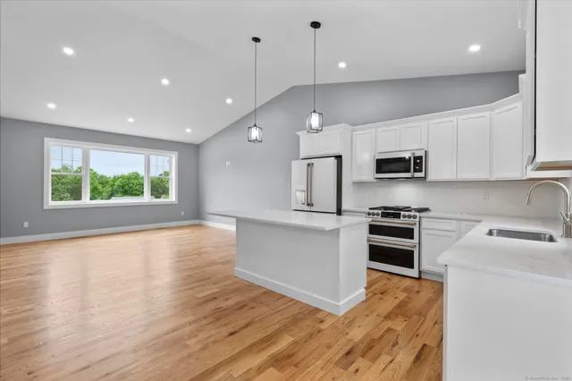 a large kitchen with stainless steel appliances granite countertop a stove a sink and a microwave