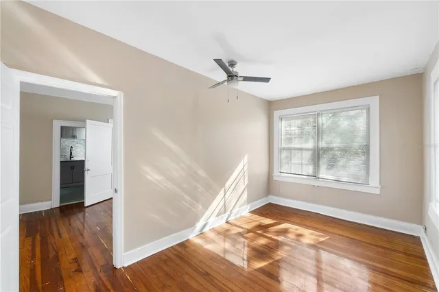 a view of an empty room with wooden floor and a window