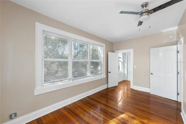 a view of an empty room with wooden floor and a window