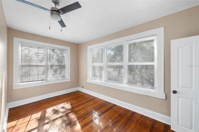 a view of an empty room with a window and wooden floor