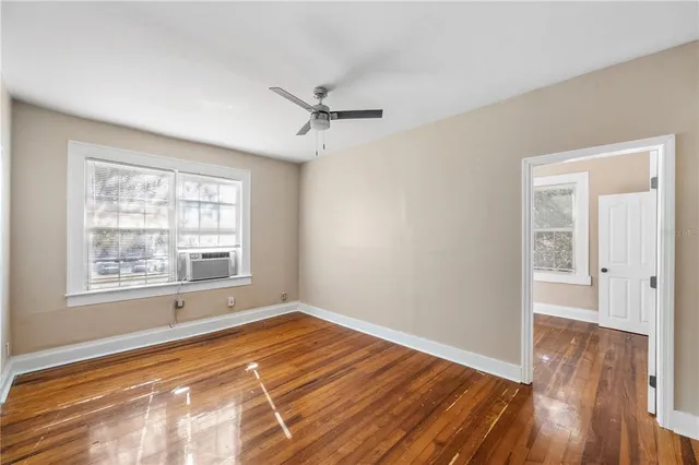 a view of an empty room with wooden floor and a window